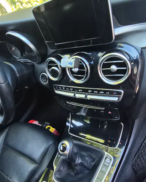 Het dashboard en de middenconsole van een auto met drie ronde ventilatieroosters, een scherm en een versnellingspook